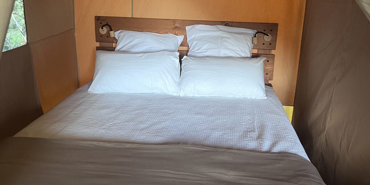 Chambre de la tente safari avec un lit double préparé, sous la toile beige