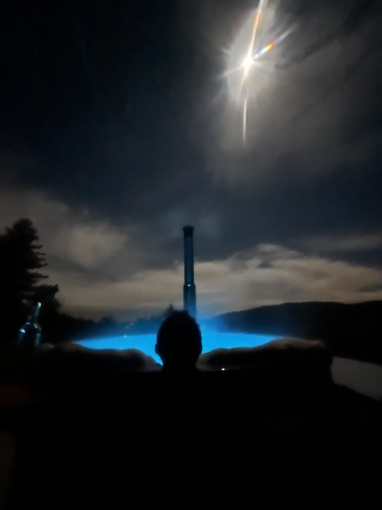 Bain nordique éclairé dans la nuit, sous la lune, au milieu du domaine