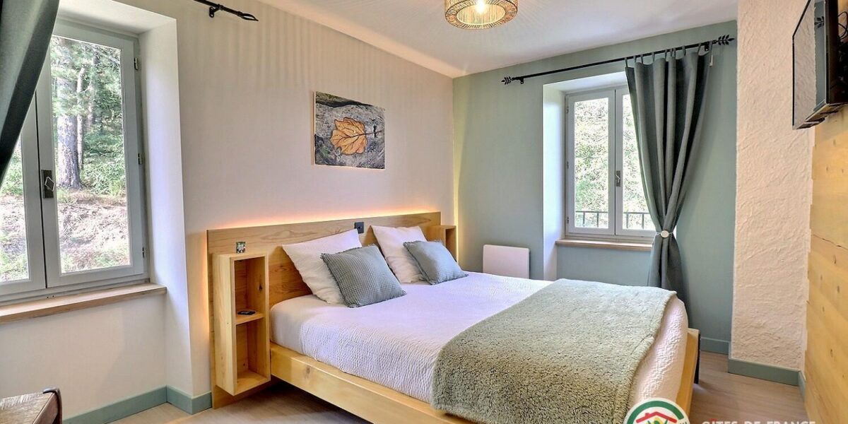 470844-10_309700_9a488aac78ce2e480ab2ce1ee65e44d0 Chambre du gîte avec un lit double face à une fenêtre ouverte sur la forêt