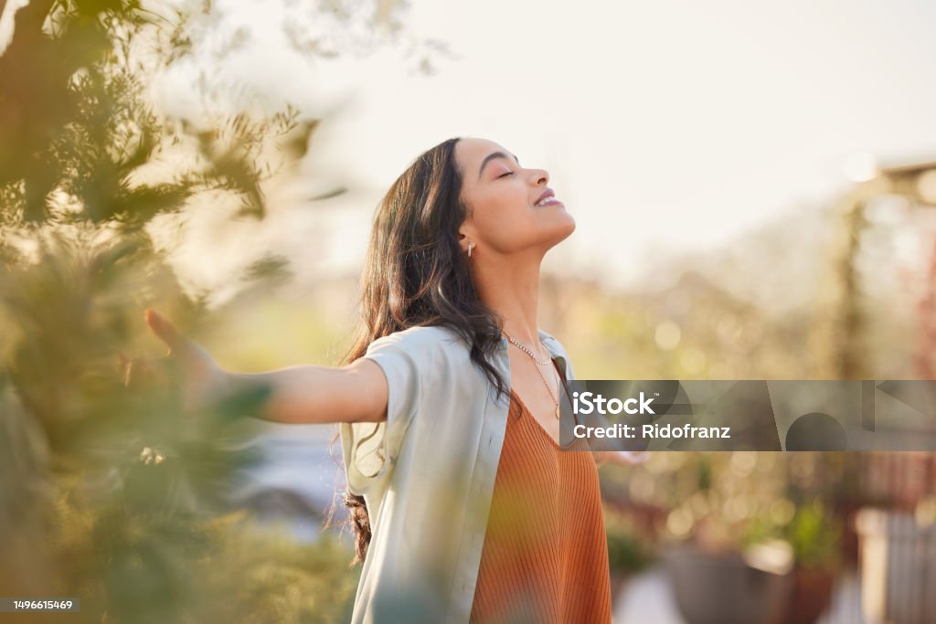 Femme bras ouverts, visage tourné vers le soleil, en pleine nature