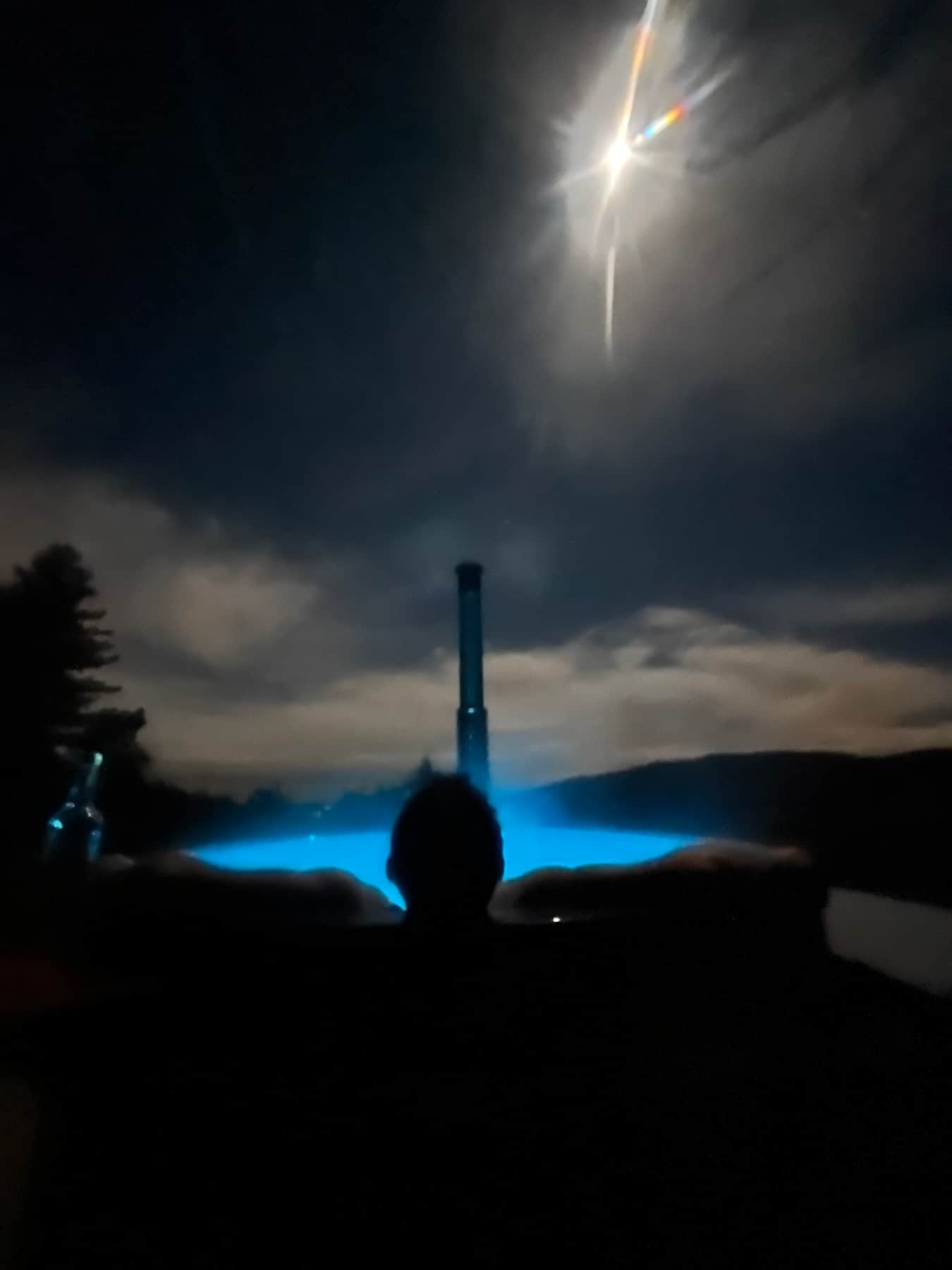 Bain nordique éclairé en bleu dans la nuit, vapeur au-dessus de l’eau